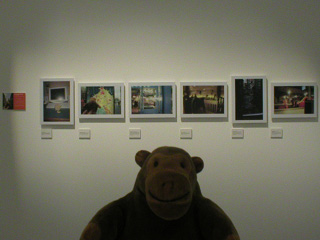 Mr Monkey in front of a row of pictures