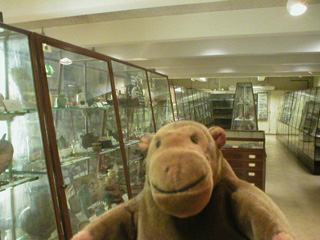 Mr Monkey in front of a row of cabinets full of Egyptian artefacts