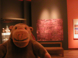 Mr Monkey in front of a red sandstone panel