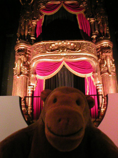 Mr Monkey in front of a replica theatre box