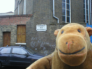 Mr Monkey in front of an odd sign reading Commit No Nuisance