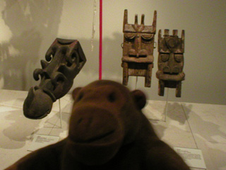 Mr Monkey in front of African masks representing hippos