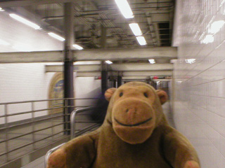 Mr Monkey in front of a mural in a subway station