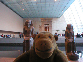 Mr Monkey in front a pair of seated statues