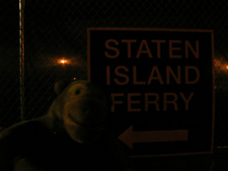 Mr Monkey in front of a sign for the Staten Island Ferry