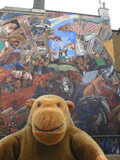Mr Monkey in front of the left hand Cable Street mural