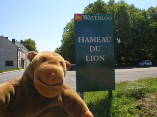 Mr Monkey with a sign saying Hameau du Lion