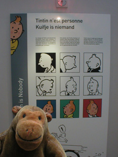 Mr Monkey in front of a display about Tintin, boy reporter