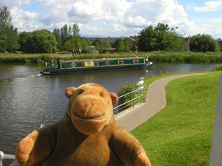 Mr Monkey watching a narrowboat going down a canal