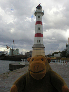 Mr Monkey in front of a red and white lighthouse