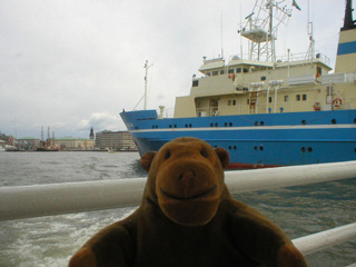 Mr Monkey looking at a large blue ship heading up the river