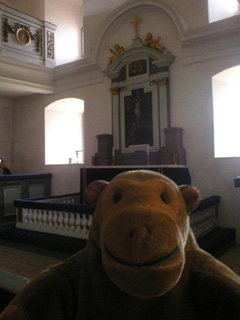 Mr Monkey looking at the altar in a small white-painted church
