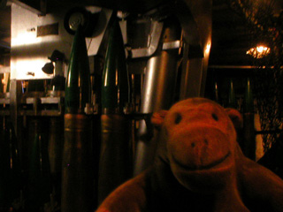 Mr Monkey in front of rack of 120mm ammunition
