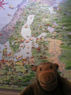 Mr Monkey in front of a map of 17th century Sweden