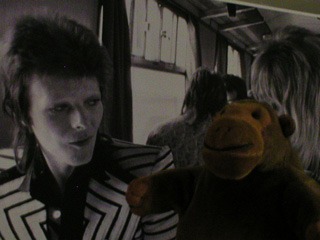 Mr Monkey in front of giant picture of David Bowie