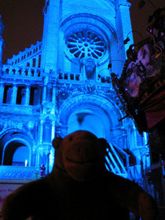 Mr Monkey looking at the blue-lit front of Ste. Cathérine's church