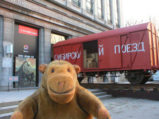 Mr Monkey looking at a bright red railway van