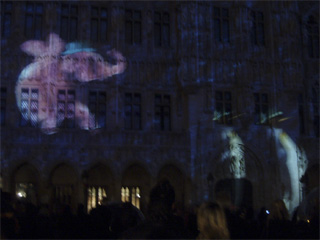 A pink elephant and two penguins projected onto the Hotel de Ville