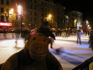 Mr Monkey watching skaters on an ice rink