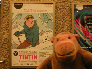 Mr Monkey in front of a poster advertising TinTin