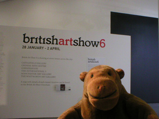 Mr Monkey in front of the Urbis British Art Show 6 sign