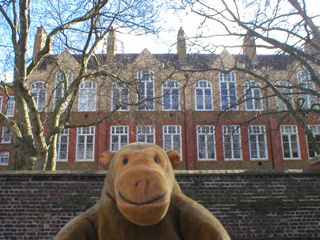 Mr Monkey peering over a wall at the old Hugh Myddleton school