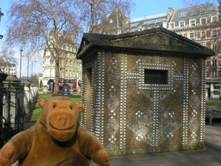 Mr Monkey in front of an ornamental tool shed