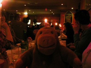 Mr Monkey with a long table full of his friends eating pizza