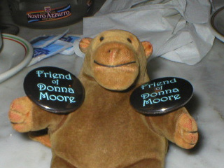 Mr Monkey holding a pair of 'Friend of Donna Moore' badges