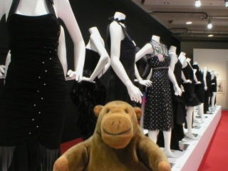 Mr Monkey looking at a row of designer dresses