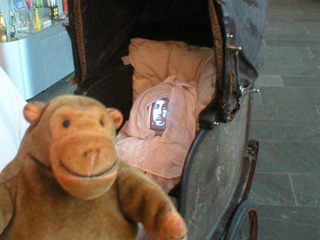Mr Monkey examining a TV screen in an old pram