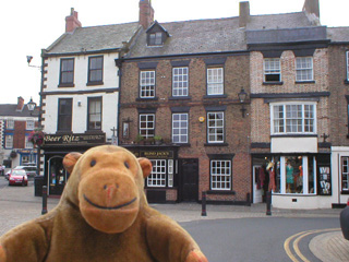 Mr Monkey looking at a row of old buildings in Knaresborough