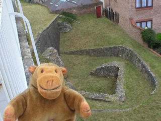 Mr Monkey looking down at the ruins of a Roman corner tower