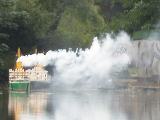 A green ship followed by a black ship, wreathed in smoke