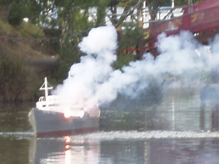 A merchant ship with flame and smoke amidships