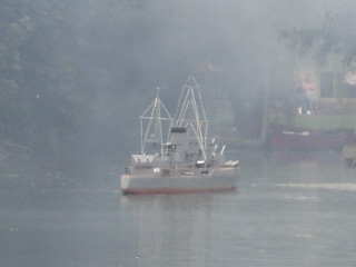 A warship facing the island, in a light haze of smoke