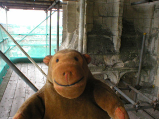Mr Monkey walking carefully around scaffolding at the top of the east front