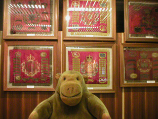 Mr Monkey looking at a collection of framed cavalry colours