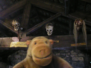 Mr Monkey looking at skulls hanging from a beam in Micklegate Bar museum