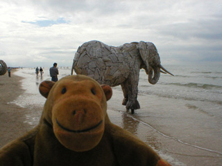 Mr Monkey looking at an elephant standing near the sea