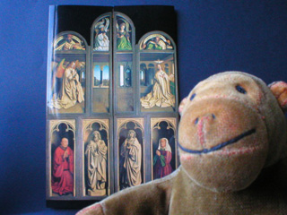 Mr Monkey in front of a postcard of the Mystic Lamb closed