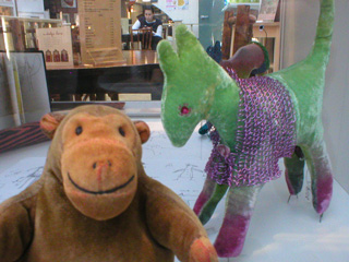 Mr Monkey very close to a green dog wearing a chainmail vest