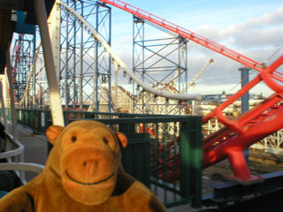 Mr Monkey looking out of the monorail at a collection of rollercoasters