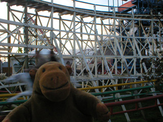 Mr Monkey looking at the Steeplechase ride and a rollercoaster